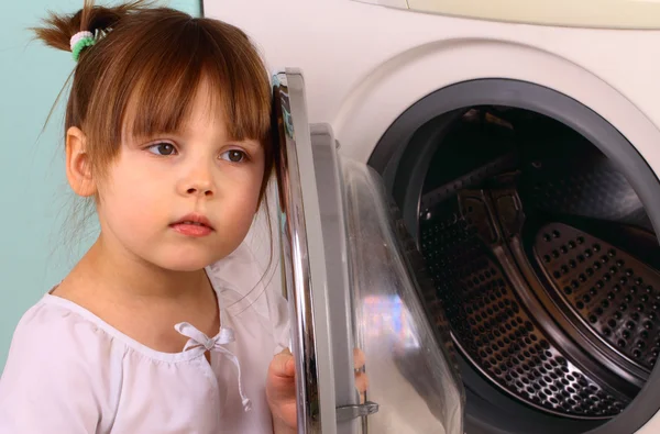 A little girl opens the washing machine — Stock Photo, Image