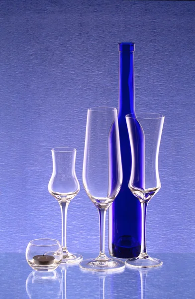 Bottiglia blu, tre bicchieri da vino e un candelabro — Foto Stock