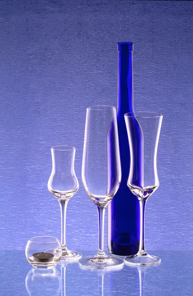 Bouteille bleue, trois verres à vin et un chandelier — Photo