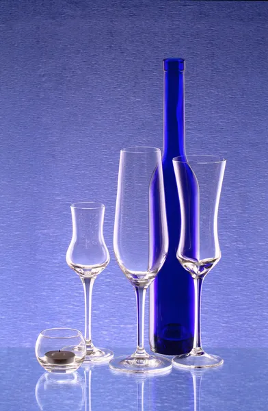 Blaue Flasche, drei Weingläser und ein Kerzenständer — Stockfoto