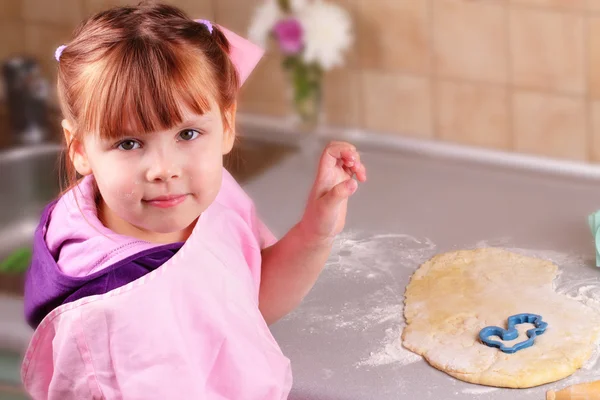 Счастливая маленькая девочка готовит печенье на кухне — стоковое фото