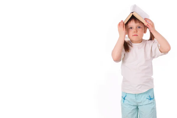 Маленькая девочка с открытой книгой на голове — стоковое фото