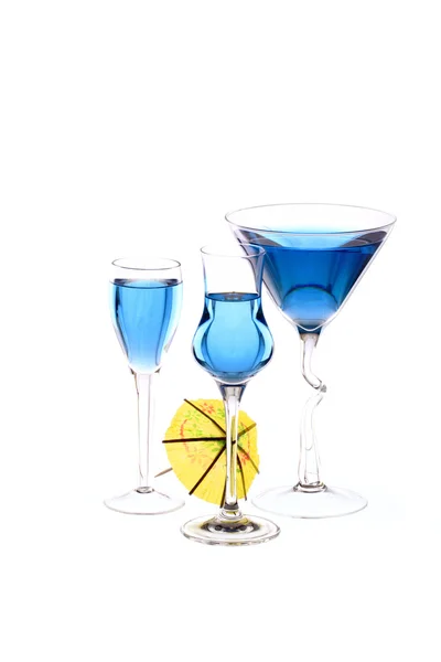 Three wineglasses are filled with blue beverage and one cocktail umbrella — Stock Photo, Image