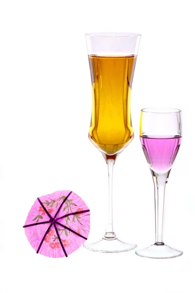 Two wineglasses are filled with colored beverages and one cocktail umbrella — Stock Photo, Image