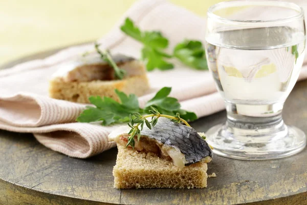 Piece of herring on rye bread on a wooden board — Stock Photo, Image