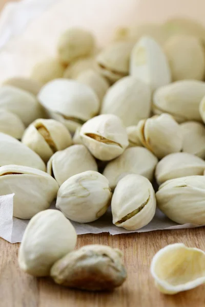 stock image Pistachio nuts in a white shell on a wooden board