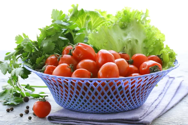 Cherry tomatoes and herbs in a wicker basket — Stock Photo, Image