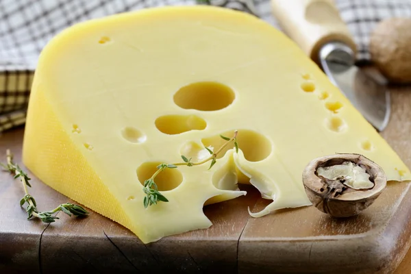 まな板の上のチーズの品種 maasdam の大きな部分 — ストック写真