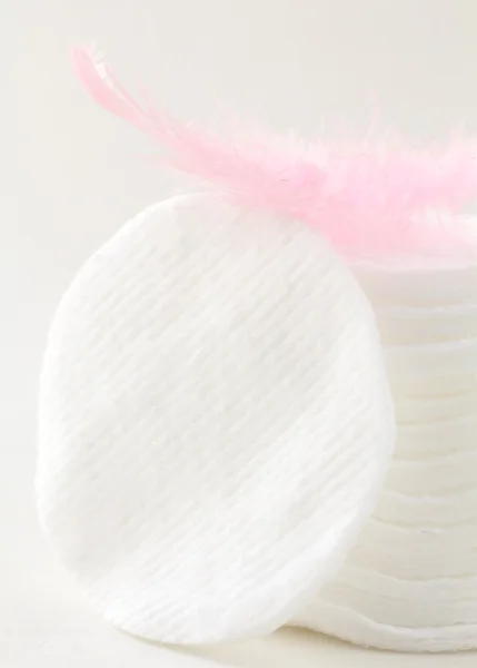 Esponjas de discos cosméticos de algodón con una pluma rosa —  Fotos de Stock