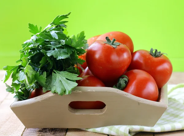 Tomates vermelhos frescos maduros e salsa em uma tigela de madeira — Fotografia de Stock