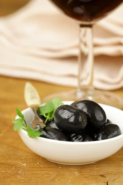 Aceitunas negras en vinagre en un tazón sobre una mesa de madera —  Fotos de Stock