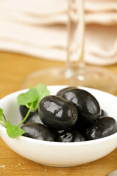 Огурцы черные оливки в миске на деревянном столе — стоковое фото