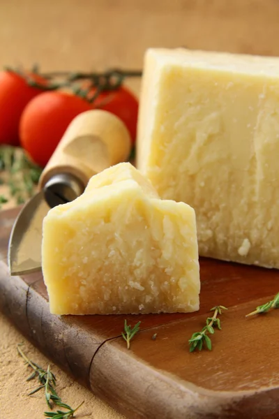 Cheese parmesan on a wooden board with tomatoes — Stock Photo, Image