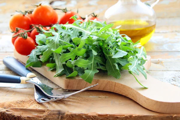 Ingredientes para la ensalada de tomate y rúcula en el tablero de la cocina —  Fotos de Stock