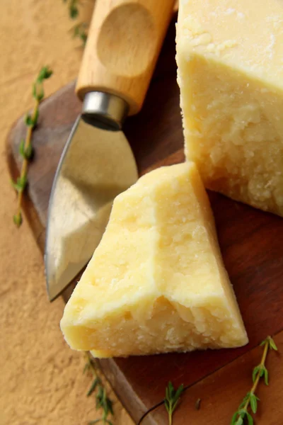 Sýr parmezán na dřevěném stole s nožem — Stock fotografie