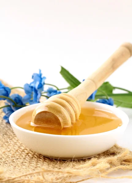 Miele d'oro fresco in vaso con cucchiaio di legno e fiori — Foto Stock