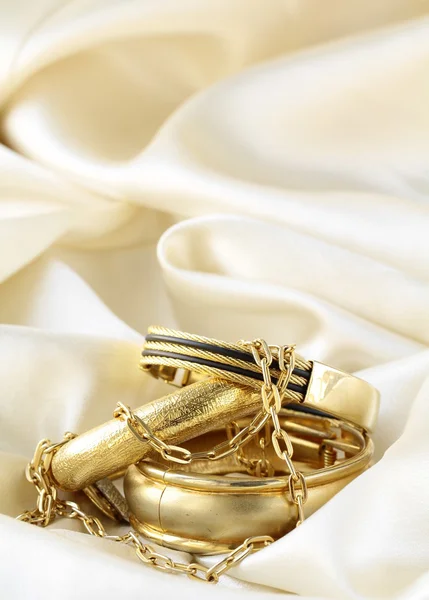 Jóias de ouro, pulseiras e correntes em seda — Fotografia de Stock