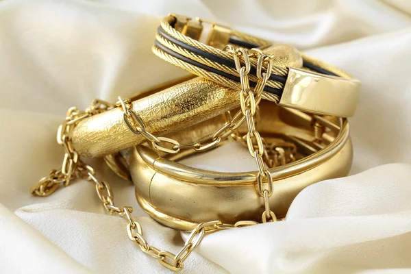 Золотые украшения, браслеты и цепи на шелке — стоковое фото