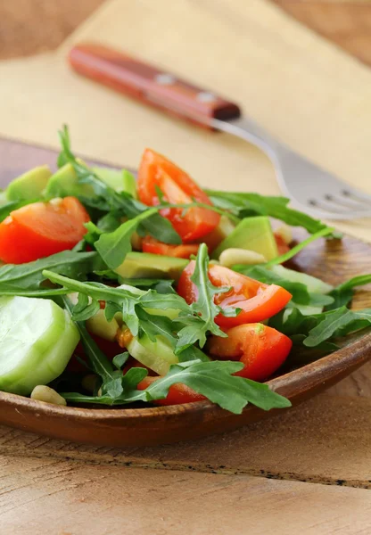 Salade avec roquette et tomates cerises sur une assiette en bois — Photo