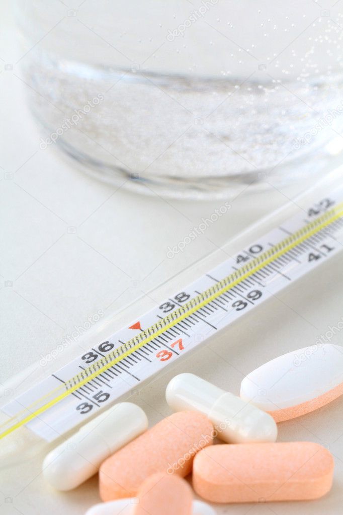 Thermometer, pills and glass with water