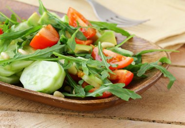 roka ve ahşap bir tabakta domates salatası