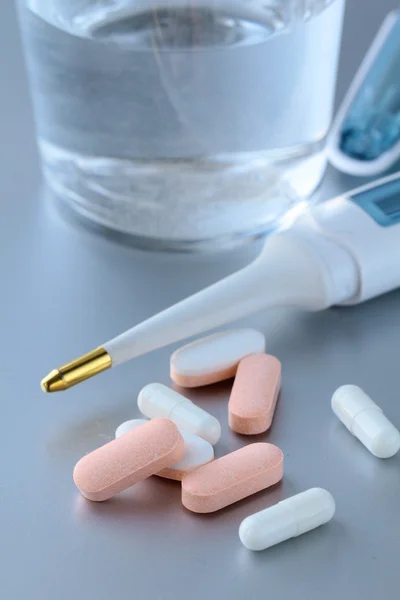 Thermometer, pills and glass with water — Stock Photo, Image
