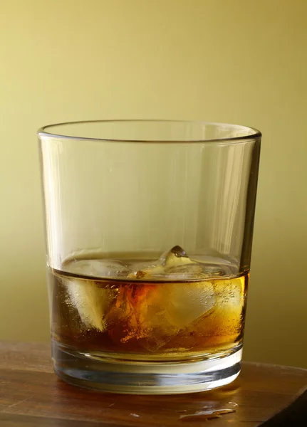 スコッチ ウイスキーとゴールドの背景に氷のグラス — ストック写真