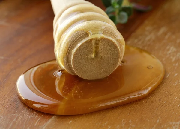 Miel fresca dorada con una cuchara de madera y flores —  Fotos de Stock