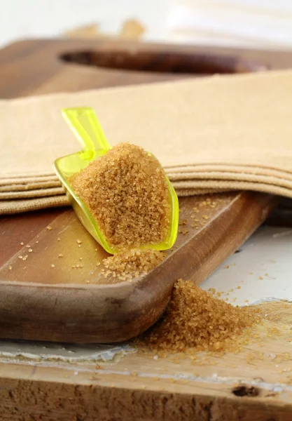 El azúcar de caña en la cuchara sobre la tabla de madera — Foto de Stock
