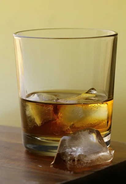 Склянка шотландського віскі та лід на золотому фоні — стокове фото