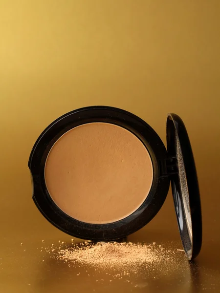 Box of powder on a gold background — Stock Photo, Image