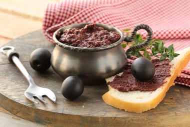 Appetizer of olives, tapenade on a wooden board clipart