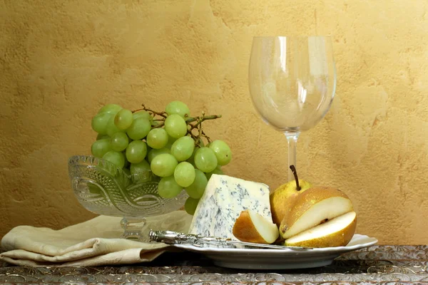 Stillleben Glas Wein, Blauschimmelkäse, grüne Trauben und Birnen auf dem Tisch, — Stockfoto