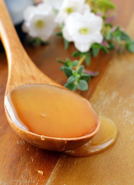 Miele d'oro fresco con cucchiaio di legno e fiori — Foto Stock