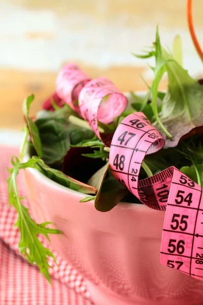 Mix salad (arugula, iceberg, red beet) with a pink measuring tape — Stock Photo, Image