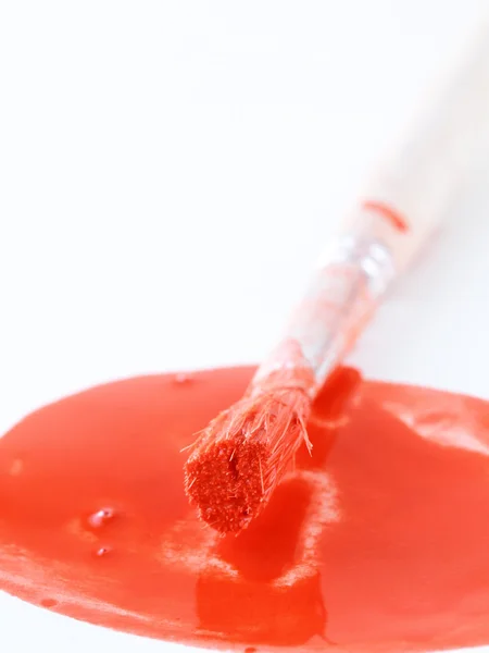 Spot röd färg och en pensel på en vit bakgrund — Stockfoto