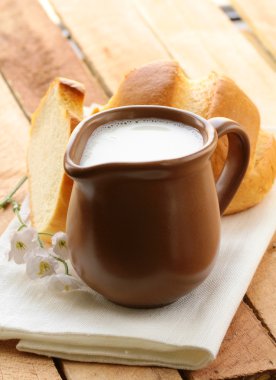 Pitcher of milk on a wooden table, rustic still life clipart