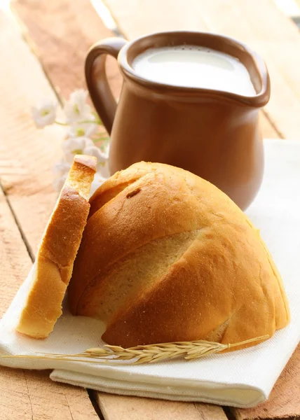 เหยือกเซรามิคกับนมและขนมปังบนโต๊ะไม้ สไตล์ชนบท — ภาพถ่ายสต็อก