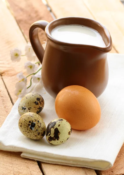 Jarro de cerâmica com leite e ovos em uma mesa de madeira, estilo rústico — Fotografia de Stock