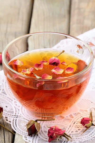 Cup of tea with dried roses on a wooden table — Stock Photo, Image