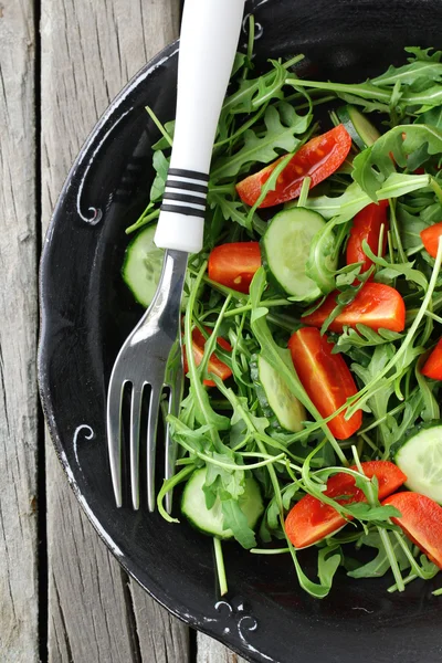 Salade met rucola en cherry tomaten op zwarte vintage plaat — Stockfoto