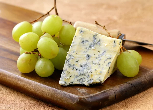 Blue cheese and white grapes on a wooden board — Stock Photo, Image