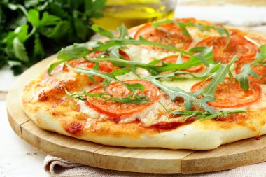 Margarita pizza with tomatoes and with arugula, on the board clipart