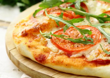 Margarita pizza with tomatoes and with arugula, on the board clipart