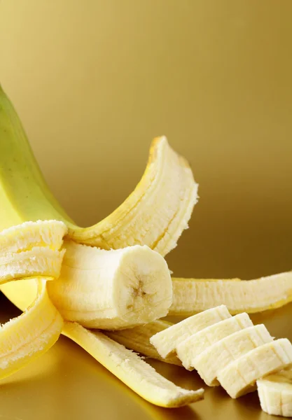Ripe banana cut into slices on a gold background — Stock Photo, Image