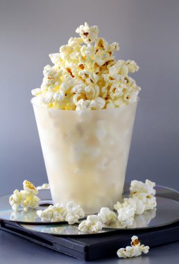Cup of popcorn and DVD disks on a gray background clipart
