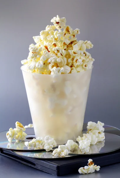 stock image Cup of popcorn and DVD disks on a gray background