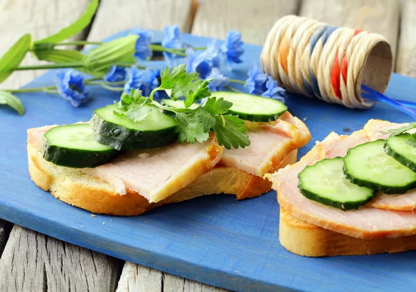 Smörgås med skinka och gurka på en trä skärbräda — Stockfoto