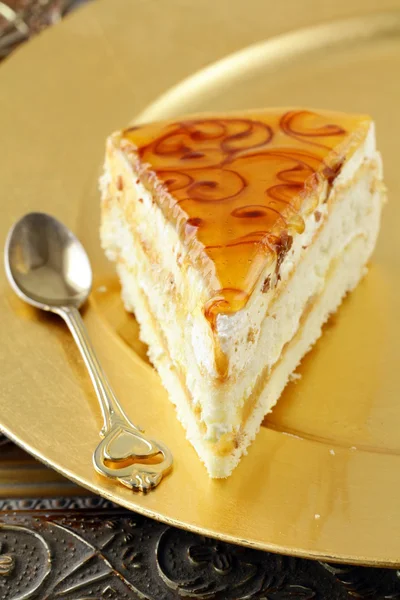 Pièce de gâteau au caramel crème sur une plaque d'or — Photo