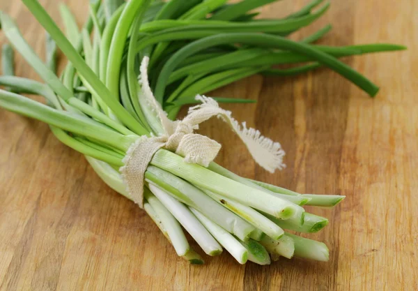 Young green organic onions on a wooden board — Stock Photo, Image